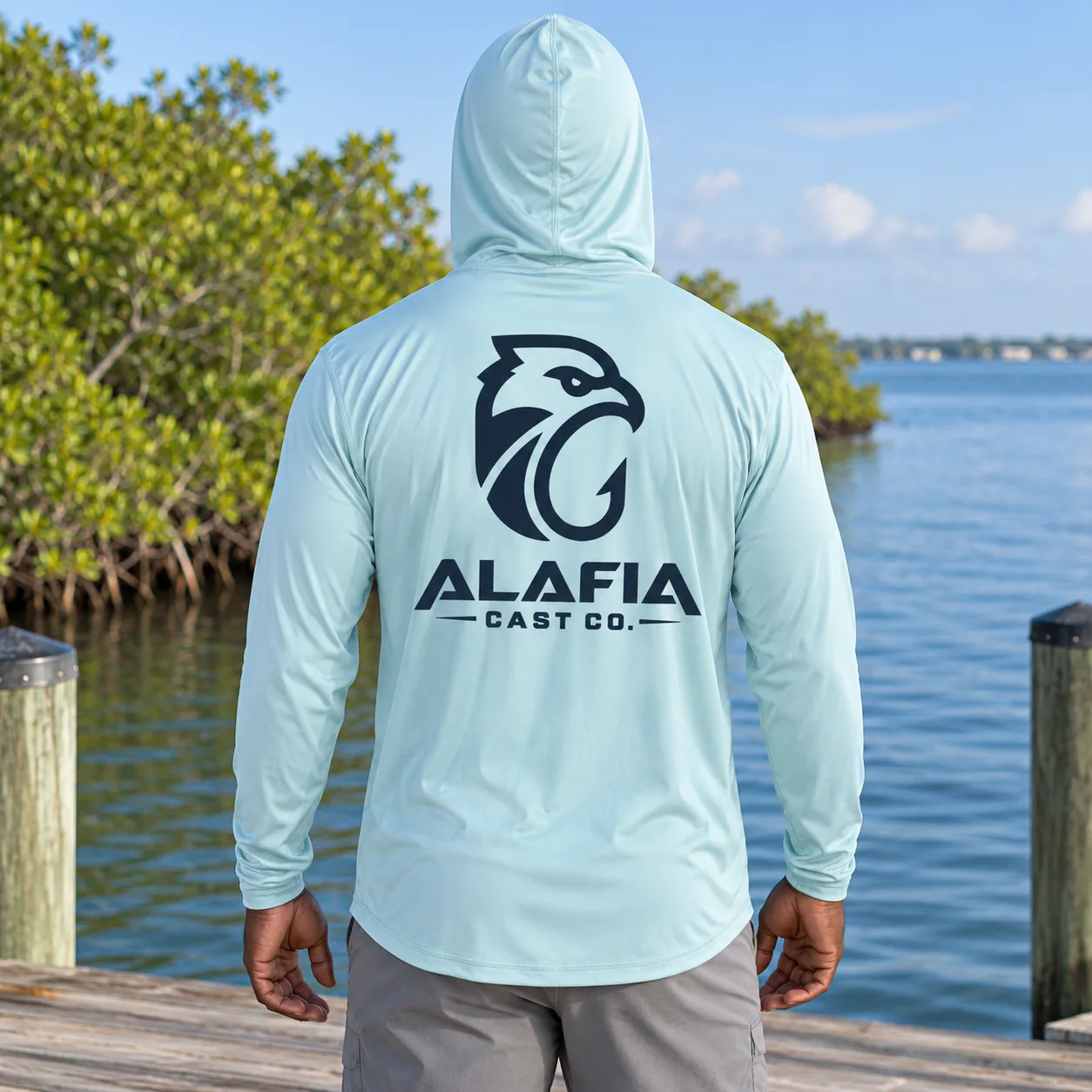 Angler on a Tampa Bay dock wearing an arctic blue Alafia Cast Co. sun hoodie with the hood up.