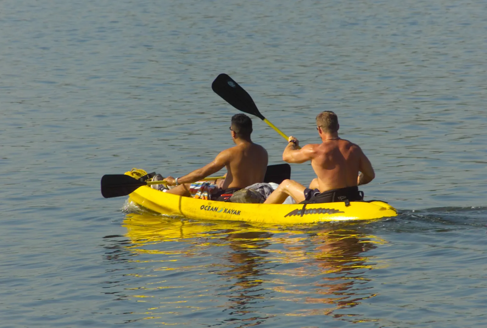 Two paddlers in a yellow tandem kayak on calm Florida bay water