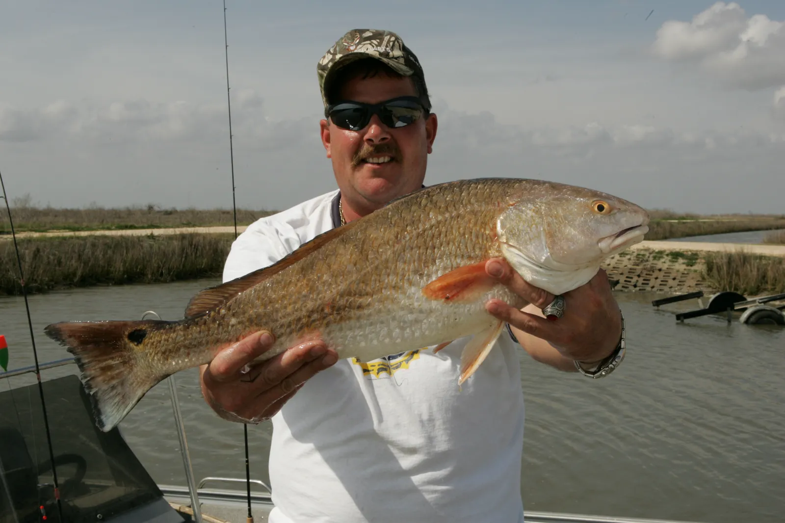 Angler holding a copper-bronze red drum with a dark spot at the base of the tail