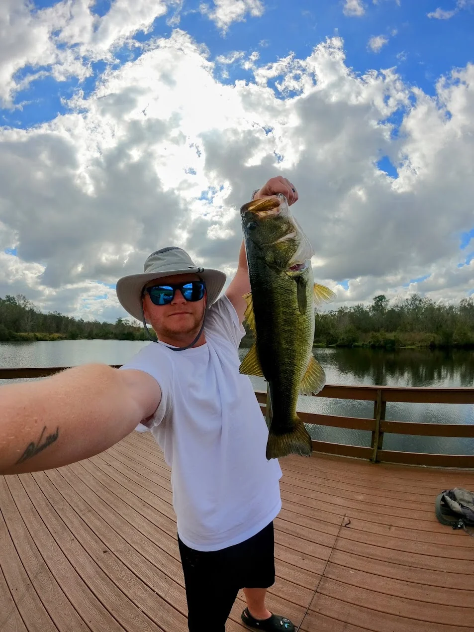 Russ holding a largemouth bass on a dock in Tampa Bay